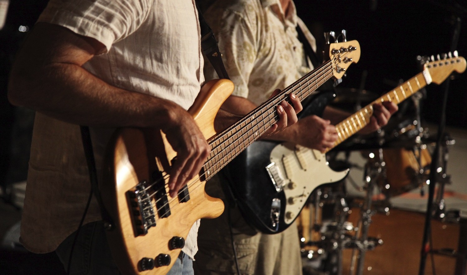 Two men, one with a bass and one with a guitar playing together.